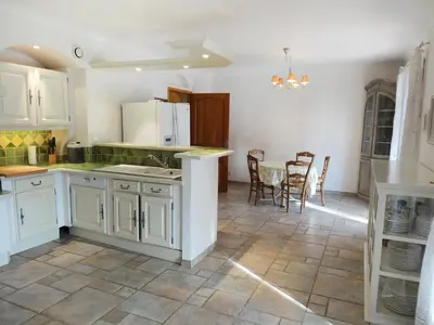 a kitchen with white cabinets and a table and chairs at Villa Le Bouloulou by Interhome in Velleron