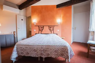 a bedroom with a bed with an orange wall at Le Moulin de Lavon in Gargas