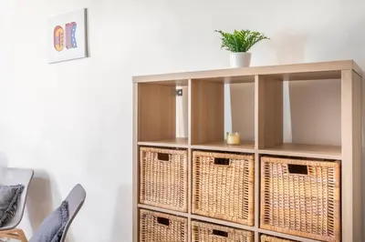 a book shelf with baskets and a plant on top at Studio place cardeurs in Aix-en-Provence
