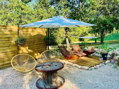 a patio with a table and chairs and an umbrella at Histoire de cru in Saignon