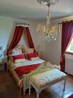 a bedroom with a bed with red curtains and a chandelier at Chambre d hôte Lavande 