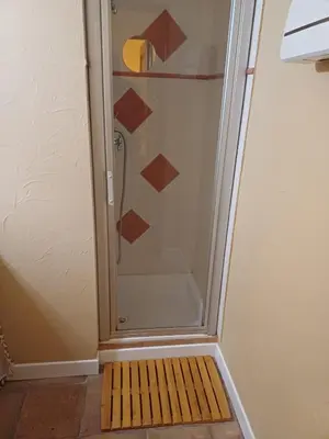 a shower with a glass door with a wooden floor at Chambre d hôte Lavande 