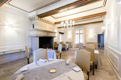 a dining room with a table and a fireplace at Moulin de Vernègues Hôtel & Spa in Mallemort