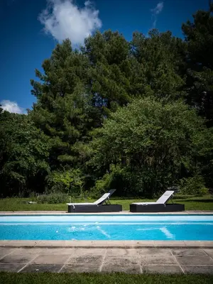 a swimming pool with two benches in a park at l'Instant Parfait in Aix-en-Provence