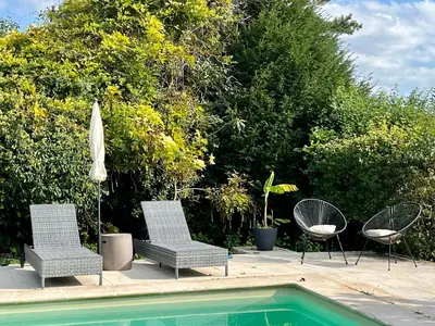 three chairs and an umbrella next to a swimming pool at Charmante maisonnette avec jardin et piscine in Aix-en-Provence