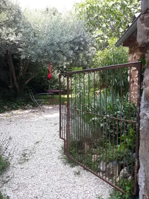 a iron gate in a garden with a swing at La maison du jardin in Rustrel
