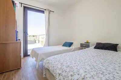 two beds in a room with a large window at Maison des Fleurs in Vedène