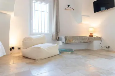 a living room with a white chair and a window at Unique guest room in the heart of Provence 