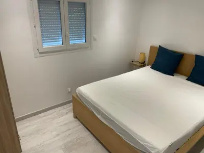 a bedroom with a bed with blue pillows and a window at Joli logement au pied des Alpilles in Eyguières