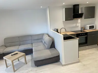 a living room with a couch and a kitchen at Joli logement au pied des Alpilles in Eyguières