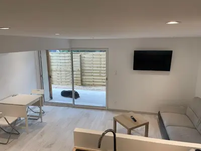 a living room with a couch and a tv on a wall at Joli logement au pied des Alpilles in Eyguières
