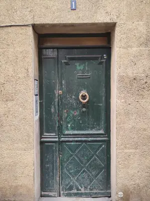 a green door in a stone building with ajar at Studio cosy place de la mairie in Aix-en-Provence