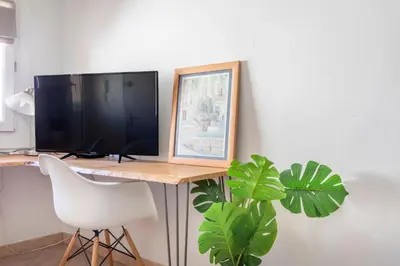 a desk with a computer monitor and a white chair at Studio cosy place de la mairie in Aix-en-Provence