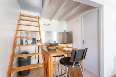 a kitchen with a ladder and a table and chairs at Studio cosy place de la mairie in Aix-en-Provence