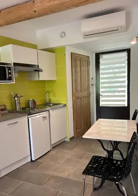a kitchen with white cabinets and a table and chairs at Gîte Nature en Luberon in Céreste