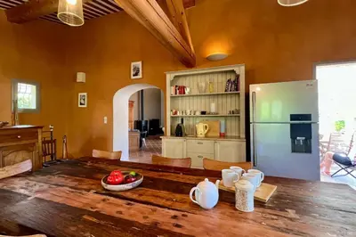 a kitchen with a wooden table and a refrigerator at Maison Marie Provençal Elegance on the Pont Royal Golf Course in Mallemort