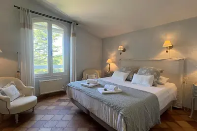 a bedroom with a bed and a chair and a window at Villa Maya Large villa and amazing pool in Luberon in Puget