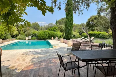 a patio with a table and chairs next to a swimming pool at Villa Maya Large villa and amazing pool in Luberon in Puget