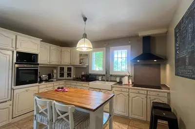 a kitchen with a wooden table and white cabinets at Villa Maya Large villa and amazing pool in Luberon in Puget