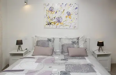 a bedroom with a bed with two lamps and a painting at Gîte les iris in LʼIsle-sur-la-Sorgue