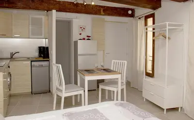 a kitchen with a table and chairs and a refrigerator at Gîte les iris in LʼIsle-sur-la-Sorgue
