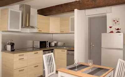 a kitchen with a table with two wine glasses on it at Gîte les iris in LʼIsle-sur-la-Sorgue
