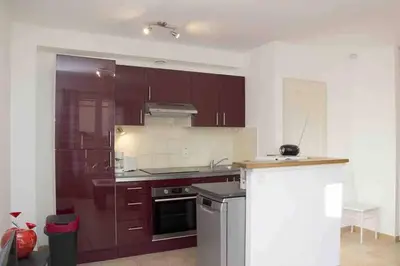 a kitchen with brown cabinets and a stove top oven at Gîte les coquelicots 2 Quartier résidentiel ( 2 * ) in LʼIsle-sur-la-Sorgue