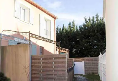 a fence in front of a house with a building at Gîte les coquelicots 2 Quartier résidentiel ( 2 * ) in LʼIsle-sur-la-Sorgue