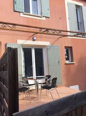 a patio with chairs and tables and a building at Gîte les coquelicots 2 Quartier résidentiel ( 2 * ) in LʼIsle-sur-la-Sorgue