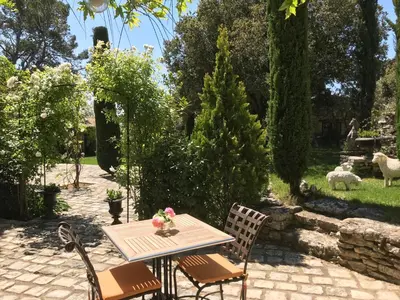 a table and chairs in a garden with sheep at Villa Hautvallon - Peaceful Escape in Provence in Gordes