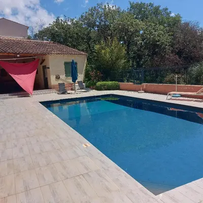 a swimming pool with blue water in a yard at Lou Cigalon in Cabrières-dʼAvignon
