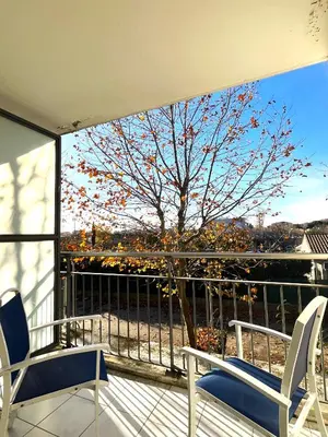 a balcony with two chairs and a tree at Les appartements du Clos de la Chartreuse By Ateya in Aix-en-Provence