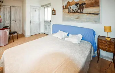 a bedroom with a blue bed and a painting on the wall at Nice Home In Venasque With Kitchen in Venasque