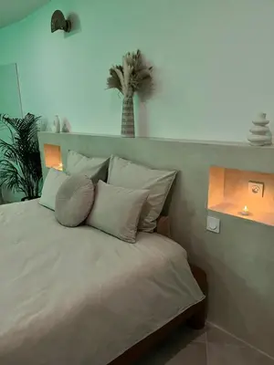 a bed with white pillows and a palm tree in a room at La Suite du clocher in Noves