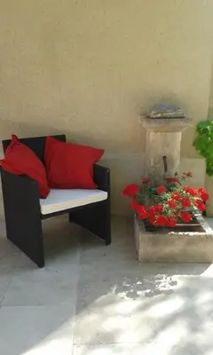 a couch with two red pillows next to a fountain at L'AMANDERAIE PISCINE PRIVEE à côté de LOURMARIN LUBERON in Cadenet
