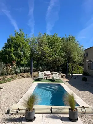 a swimming pool with two chairs and a table at L'AMANDERAIE PISCINE PRIVEE à côté de LOURMARIN LUBERON in Cadenet
