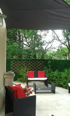 a patio with two chairs and a table with red pillows at L'AMANDERAIE PISCINE PRIVEE à côté de LOURMARIN LUBERON in Cadenet