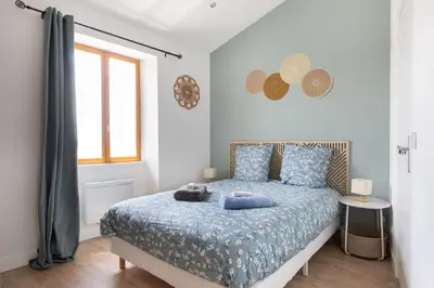 a bedroom with a bed with a blue comforter and a window at L'Isle en Blanc - 4 couchages - Hypercentre - Clim - Wifi in LʼIsle-sur-la-Sorgue