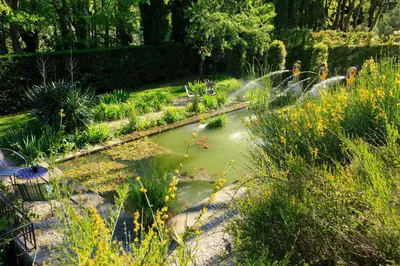 a patio with a table and umbrellas and flowers at Mas de L'Amarine in Saint-Rémy-de-Provence