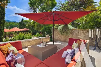a woman walking into a house with a red umbrella at Mas de L'Amarine in Saint-Rémy-de-Provence
