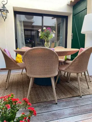 a patio with chairs and a table with a vase of flowers at La RENAUDIERE in LʼIsle-sur-la-Sorgue