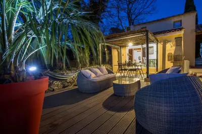 a deck with couches and a table on a house at El Sama-In , Piscine chauffée in LʼIsle-sur-la-Sorgue