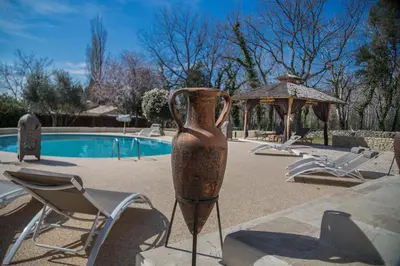 a vase on a stand in front of a pool at El Sama-In , Piscine chauffée in LʼIsle-sur-la-Sorgue