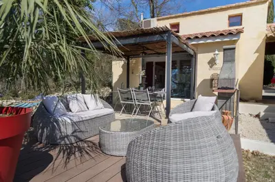 a wooden deck with wicker chairs and a table at El Sama-In , Piscine chauffée in LʼIsle-sur-la-Sorgue