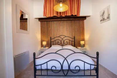 a bedroom with a bed in a room with a curtain at El Sama-In , Piscine chauffée in LʼIsle-sur-la-Sorgue