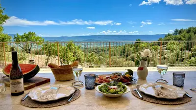 a table with a plate of food and a bottle of wine at Mas La Rose Sauvage - magnificent Luberon views in Murs