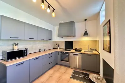 a kitchen with white cabinets and stainless steel appliances at Les Lauriers Blancs air-conditioned villa with swimming pool in LʼIsle-sur-la-Sorgue