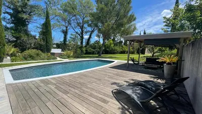 a swimming pool with a wooden deck and a pavilion at B&B 2 Chambres d'hôtes Gai Félibre avec Piscine et Jacuzzi in Le Thor