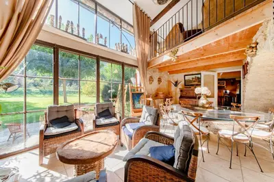 a living room with chairs and tables and windows at Mas Titourin - Moulin du 18ème entièrement rénové in Ansouis