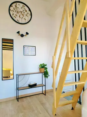 a staircase in a living room with a table and a mirror at Grand studio lumineux au calme, centre historique in Pertuis